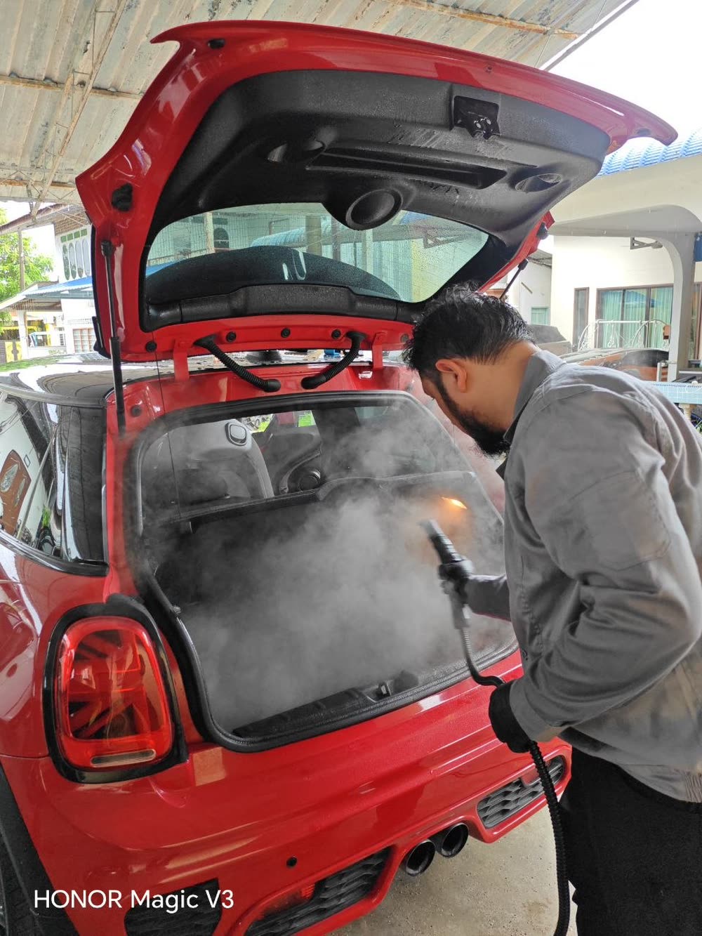 Sertu Team member steam-treating a vehicle exterior compartment